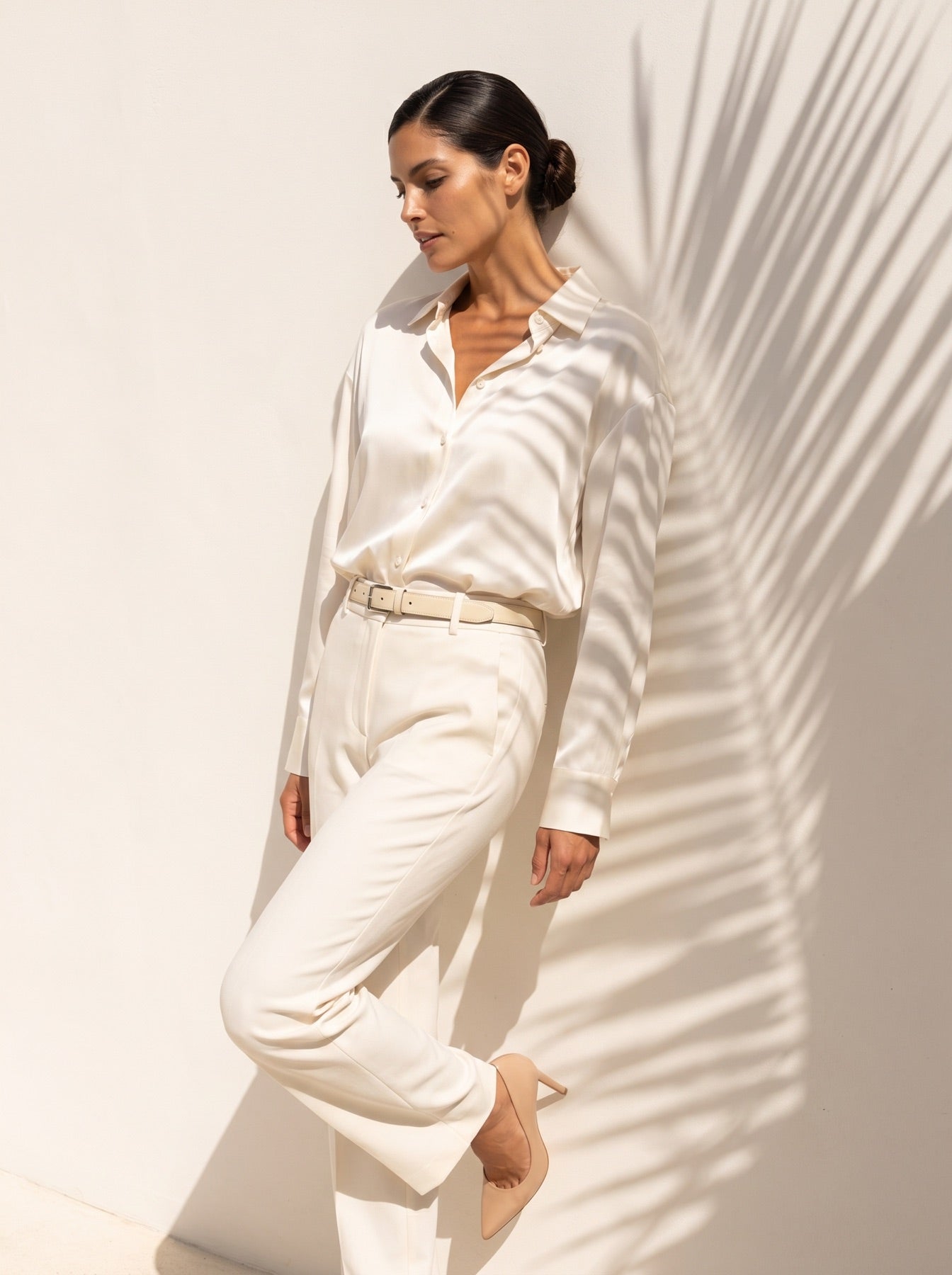 Ivory silk shirt with tailored trousers under palm shadow